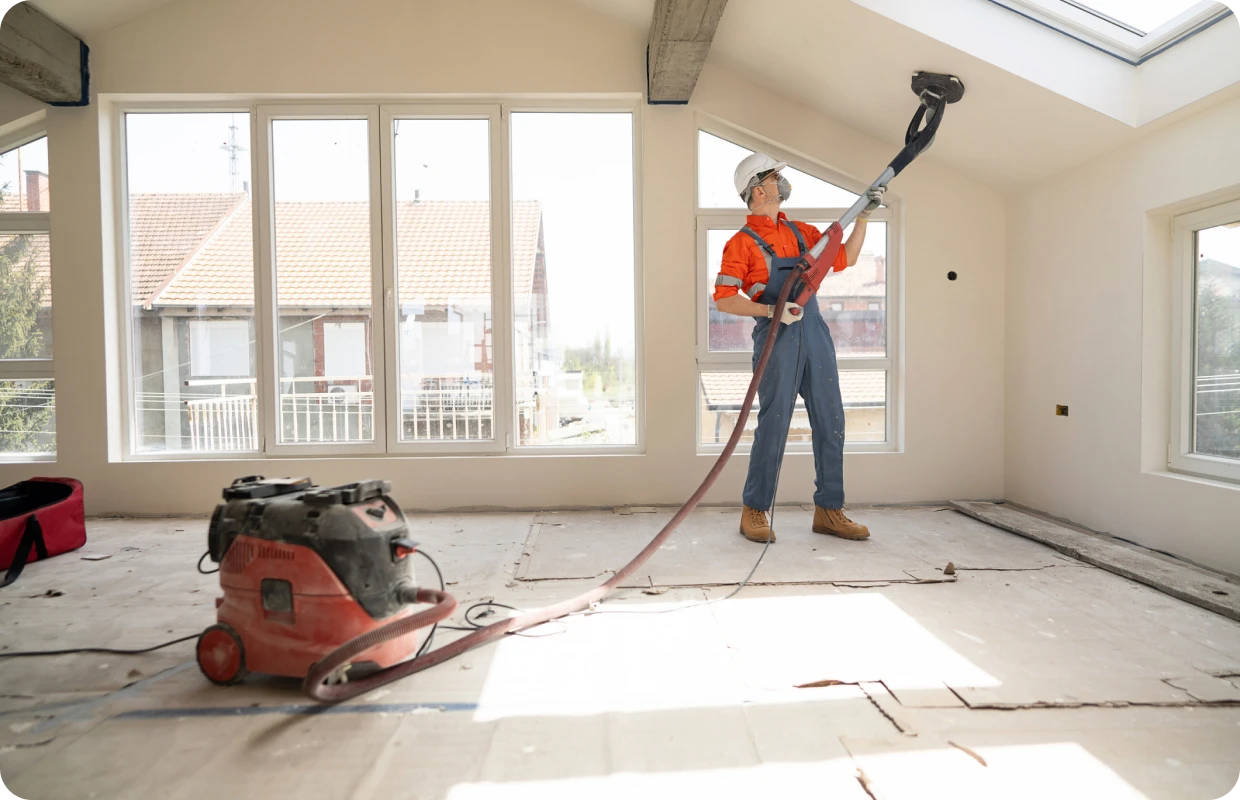 Worker using sander on ceiling renovation