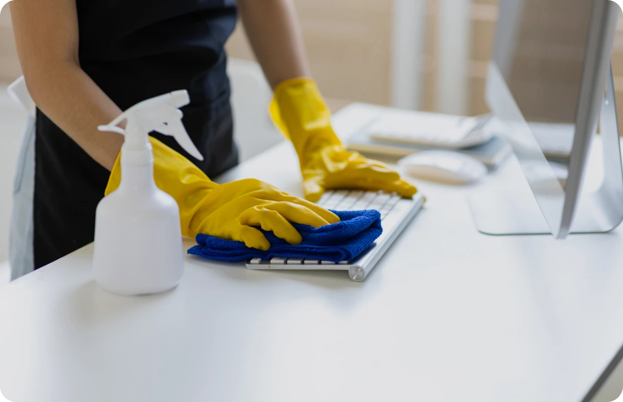 Person cleaning keyboard with gloves and cloth